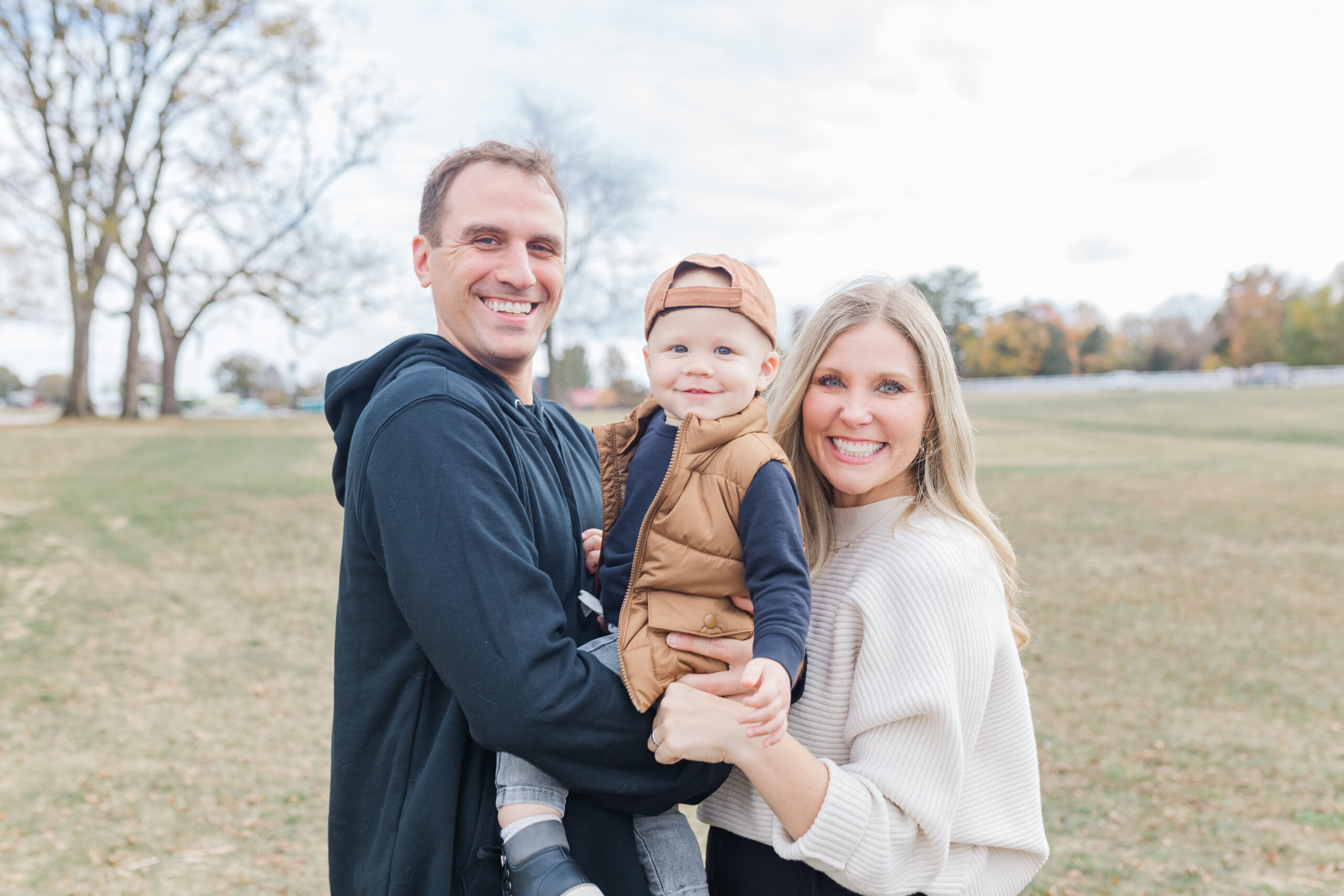 nashville-fall-mini-sessions-2025-parents-holding-child-in-autumn-park